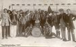 Historisches Gruppenfoto verkleideter Personen mit einer Trommel vor einem Fußballtor