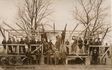Historisches Foto einer Gruppe auf einem Holzgerüst zwischen kahlen Bäumen