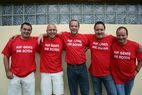 Fünf Fan-Club-Mitglieder in roten T-Shirts stehen Arm in Arm vor einer hellen Hauswand