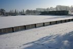 Schneebedecktes Spielfeld mit Tribüne im Winter