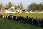 Zuschauer an der Bande, im Hintergrund das Vereinsheim