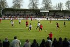 Spielszene vor der Tribüne mit Spielern in roten und weißen Trikots