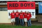 Fünf Mitglieder des Fan-Clubs „Red Boys“ in roten T-Shirts vor einem großen rot-weißen Banner mit der Aufschrift „RED BOYS HASSFURT“
