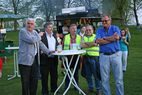 Männer an einem Stehtisch am Spielfeldrand, zwei davon in Warnwesten