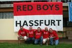 Die fünf Fan-Club-Mitglieder hocken auf dem Rasen vor dem rot-weißen Banner „RED BOYS HASSFURT“