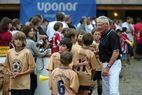 Kinder in beigefarbenen Trikots mit einem Mann in schwarzem Shirt vor einem Uponor-Banner