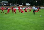 Spieler in roten Trikots beim Aufwärmen auf dem Rasen