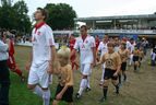 Spieler in weißen Trikots laufen mit Kindern ein
