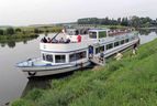 Ausflugsschiff mit Fahrgästen am Flussufer