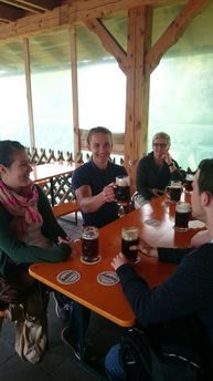 Personen stoßen am Tisch mit Bierkrügen an