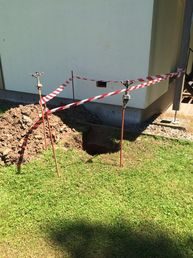 Mit Absperrband gesicherte Baugrube an einer Gebäudewand