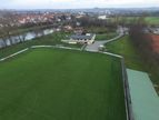 Luftaufnahme des Spielfelds mit Vereinsheim und Blick Richtung Stadt