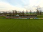 Spielfeld mit überdachter Tribüne im Hintergrund bei bewölktem Himmel