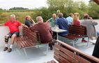 Fahrgäste auf Bänken an Deck