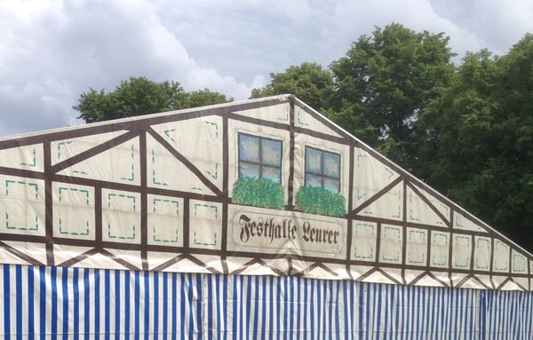 Festzelt mit aufgemalter Fachwerkfassade und blau-weiß gestreifter Seitenwand