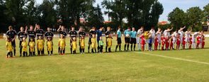 Mannschaften und Einlaufkinder in einer Reihe auf dem Spielfeld aufgestellt