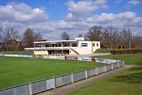 Spielfeld mit Vereinsheim im Hintergrund bei blauem Himmel
