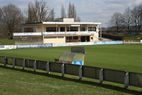Vereinsheim mit Terrasse hinter Spielfeld und Bande