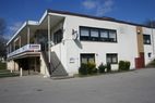 Weißes zweistöckiges Vereinsheim mit Außentreppe und Balkon