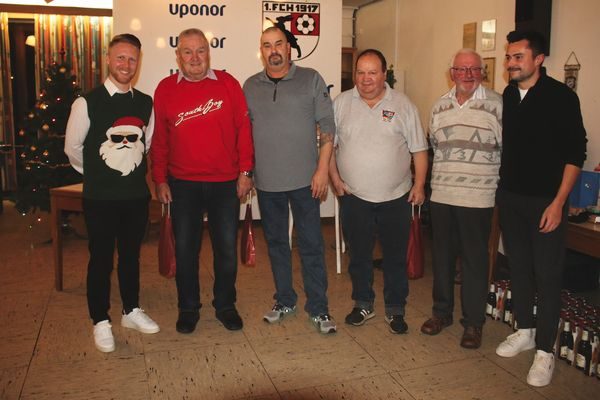 Sechs Männer, teils in Weihnachtspullovern, vor dem Uponor-Banner und dem Vereinswappen