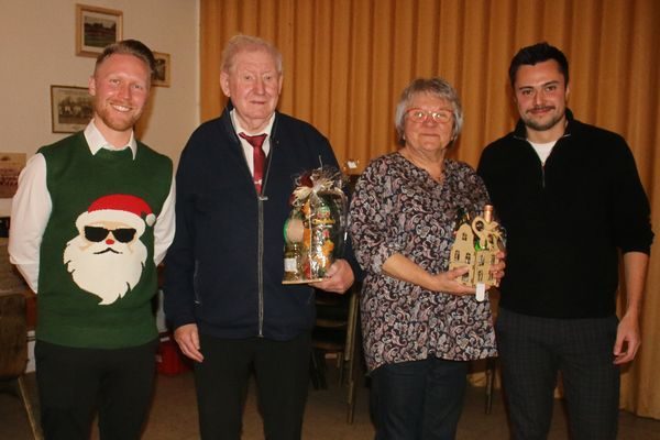Zwei ältere Gäste mit Geschenken zwischen zwei jüngeren Männern