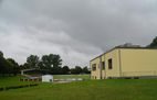Vereinsheim am Rand des Sportgeländes bei bewölktem Himmel