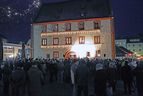 Menschenmenge vor einem beleuchteten historischen Gebäude bei Nacht
