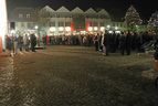 Menschenmenge auf einem beleuchteten Platz mit Weihnachtsbaum bei Nacht