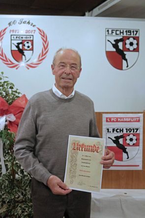 Älterer Herr mit Urkunde vor dem Vereinsbanner