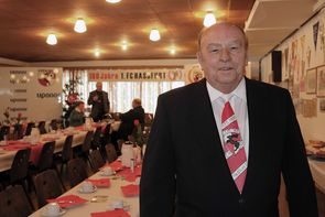 Mann in Anzug mit rot-weißer Krawatte im festlich gedeckten Saal