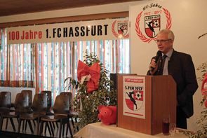 Redner am Rednerpult mit Vereinswappen vor dem Banner „100 Jahre 1. FC Hassfurt“
