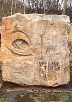 Gedenkstein mit eingemeißeltem Auge und der Inschrift „Unseren Toten“