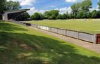 Spielfeld mit überdachter Tribüne und Bande im Sommer