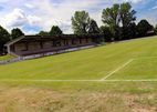 Spielfeld mit überdachter Tribüne bei Sonnenschein