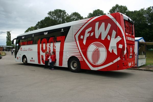 Rot-weißer Mannschaftsbus der Würzburger Kickers mit „F.W.K.“-Logo auf dem Parkplatz
