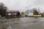 Eingangsgebäude des Stadions mit Schriftzug, davor ein nasser Parkplatz