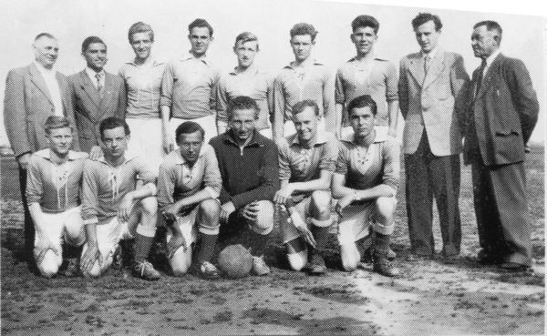 Schwarz-Weiß-Mannschaftsfoto der FC-Jugend um 1955 auf dem Sportplatz: hinten stehen fünf Spieler in hellen Trikots, eingerahmt von vier Betreuern in Anzügen; vorne knien sechs Spieler, einer im dunklen Torwartpullover, davor liegt ein Lederball.