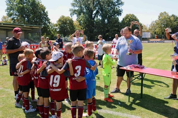 Jugendspieler bei der Siegerehrung, ein Mann hält einen Pokal