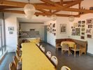Gastraum des Tennisheims mit Tischreihe und Stühlen, Holzbalkendecke, Bildern und Urkunden an der Wand und Durchgang zum Thekenbereich